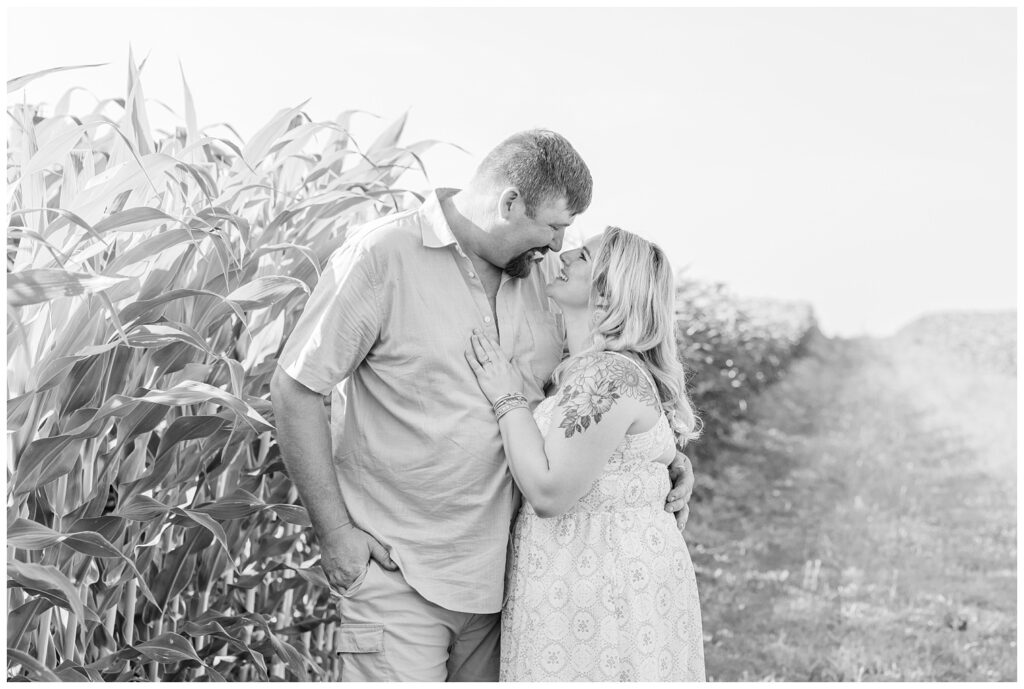 mom and dad smiling and hugging next to corn stalks for Tiffin, Ohio family session