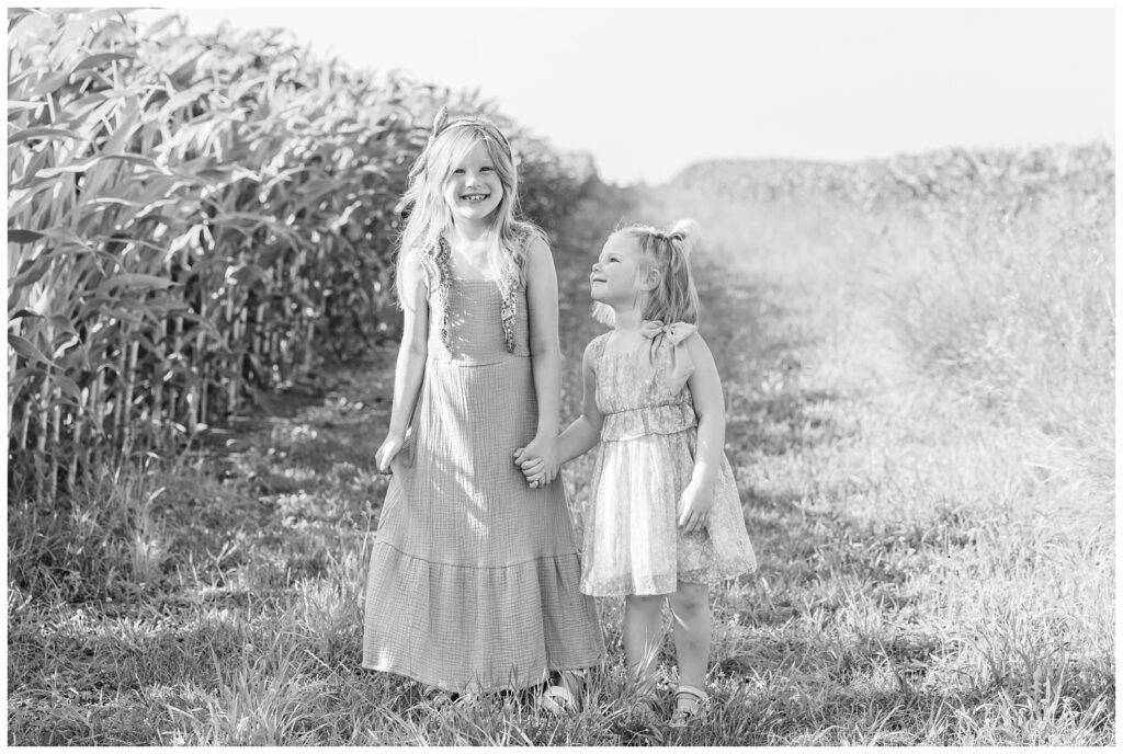 two sisters walking together next to corn stalks on a farm in Tiffin, Ohio