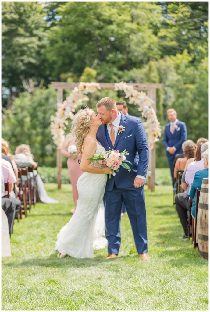 bride and groom kissing while walking back down the aisle outside in Tiffin, Ohio