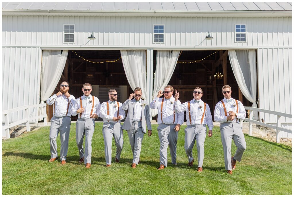 groomsmen all wearing sunglasses walking down the hill at Arlington Acres