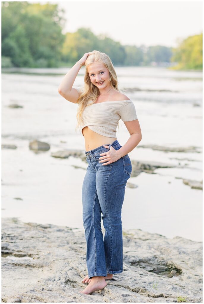 senior girl wearing a white top and jeans posing on the rocks in Fremont, Ohio