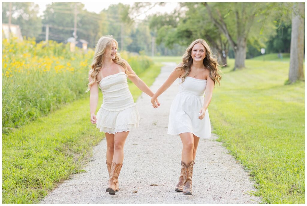two senior best friends holding hands and walking on a path at Don Miller Park