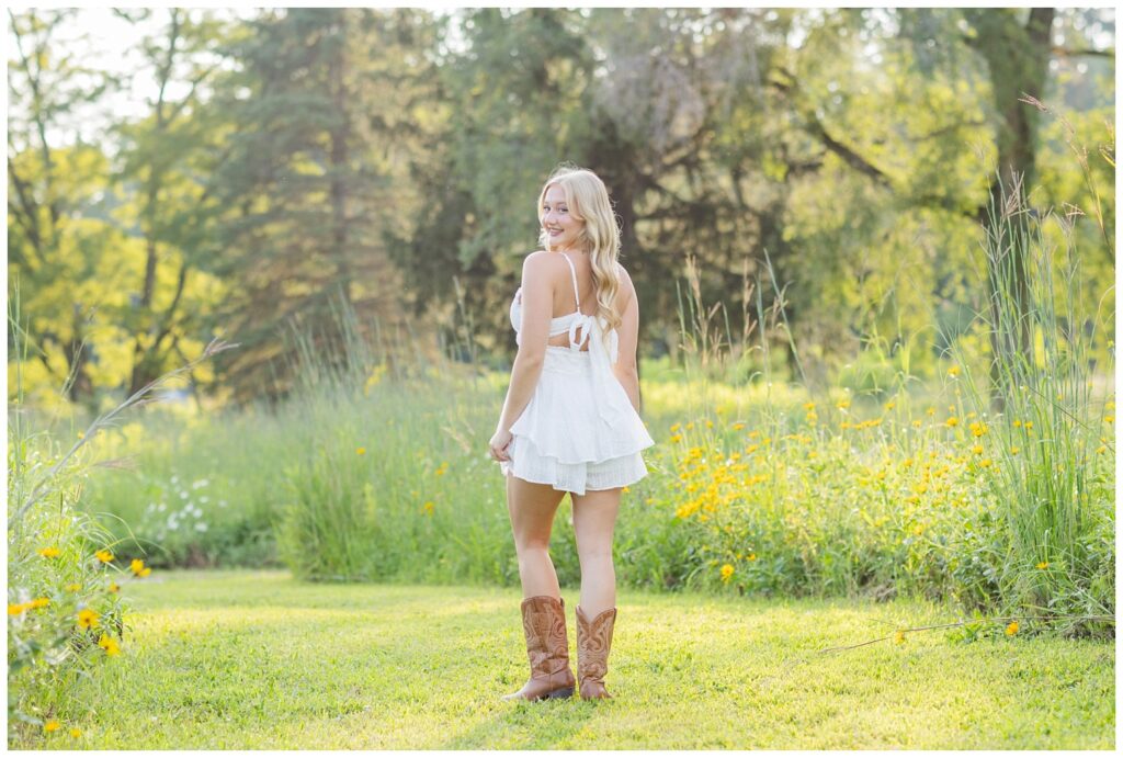 girl walking among yellow flowers in Don Miller Park for senior session