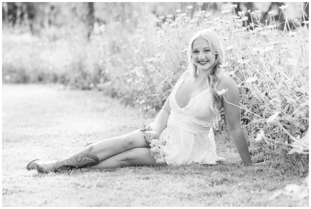 senior girl posing on the ground in front of a yellow flower field in Fremont, Ohio