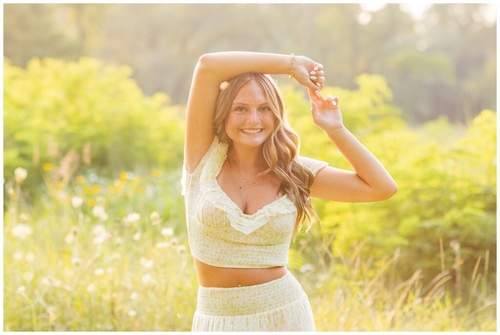 senior girl wearing a white and yellow top and skirt posing at Don Miller Park