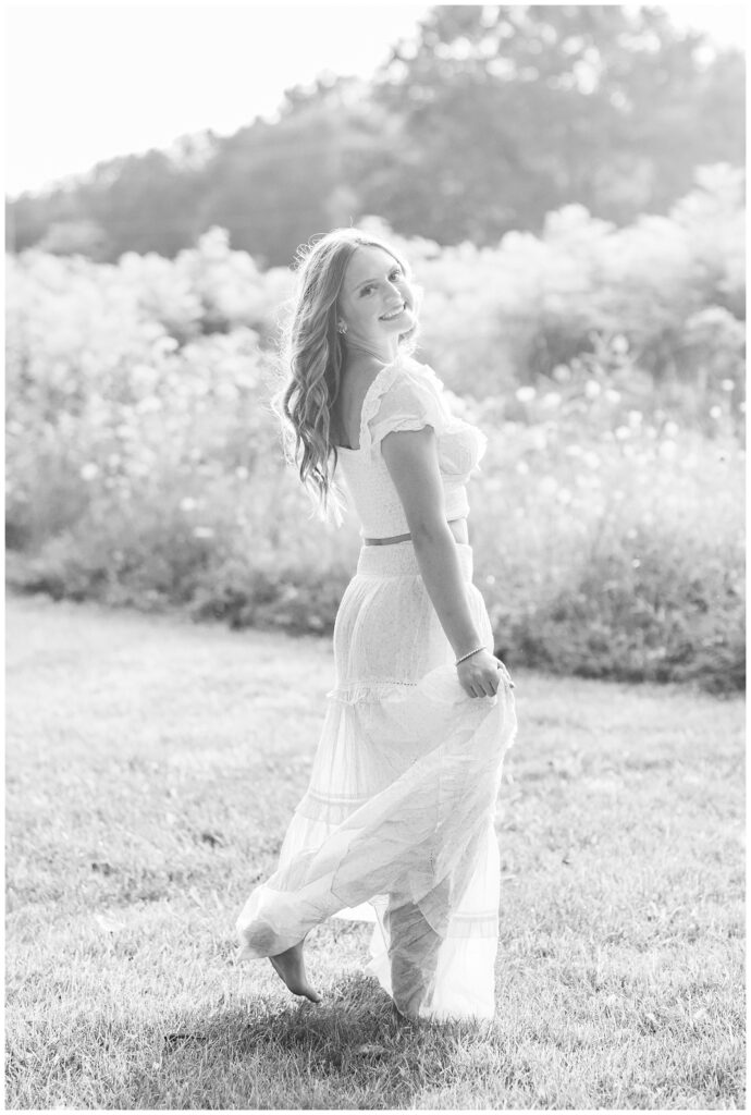 high school senior girl twirling in a white and yellow top and skirt at Don Miller Park