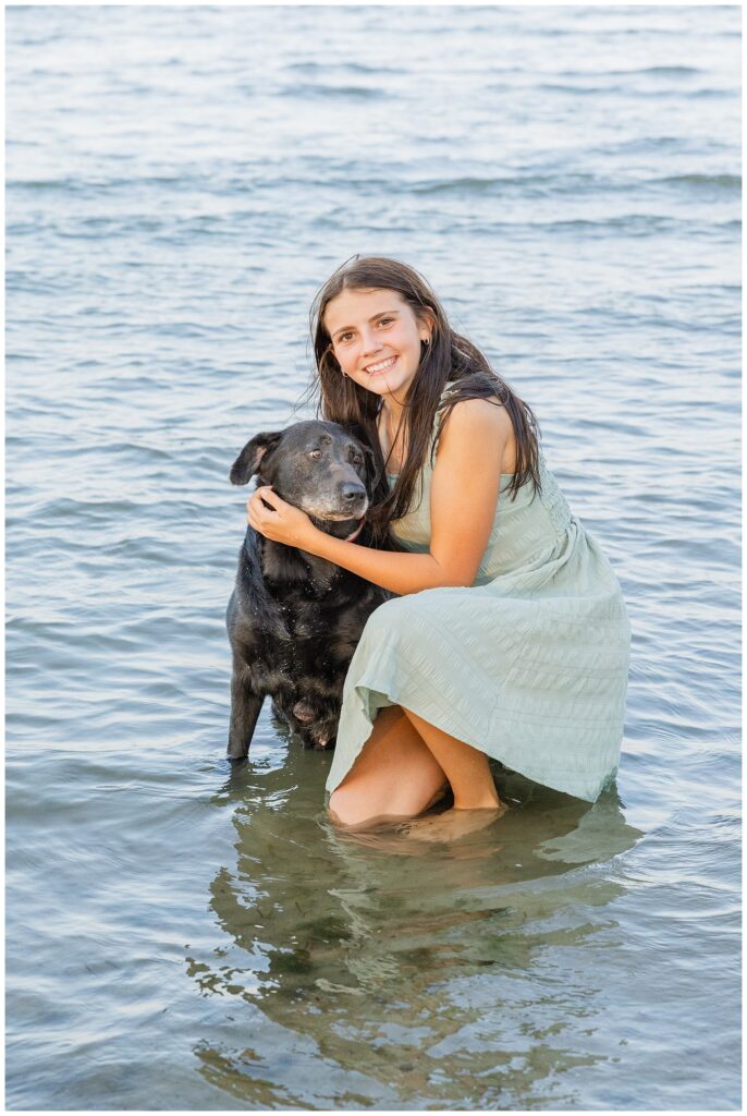 young girl holding her back dog while squatting in the water in Sandusly, Ohio