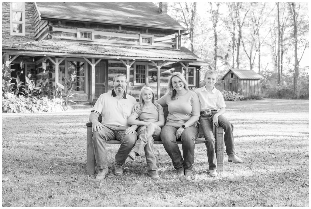 family of four posing on a bench in front of their log cabin in Tiffin, Ohio