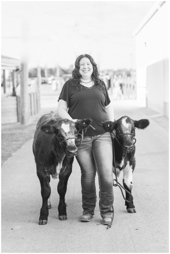 senior girl walking outside with two heifer cows at Sandusky County Fair in Ohio