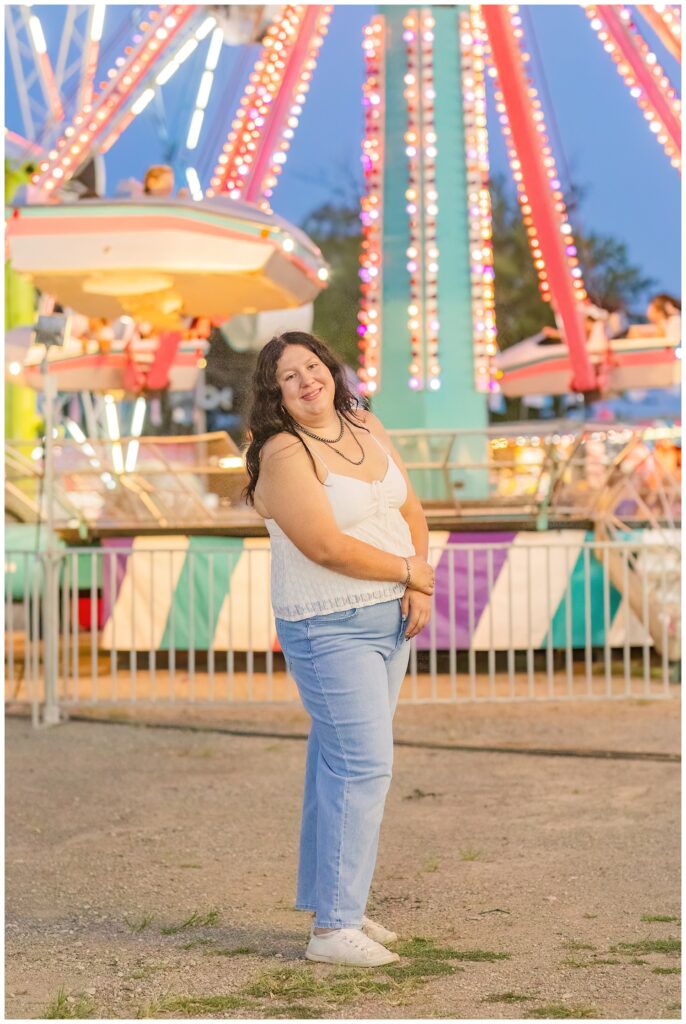 senior girl wearing jeans and white top posing at Sandusky county fair at night