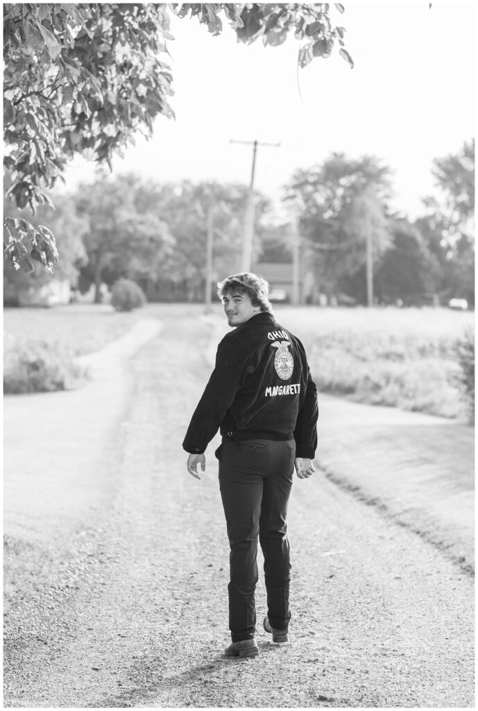 senior boy walking on the road wearing his FFA jacket in Fremont, Ohio