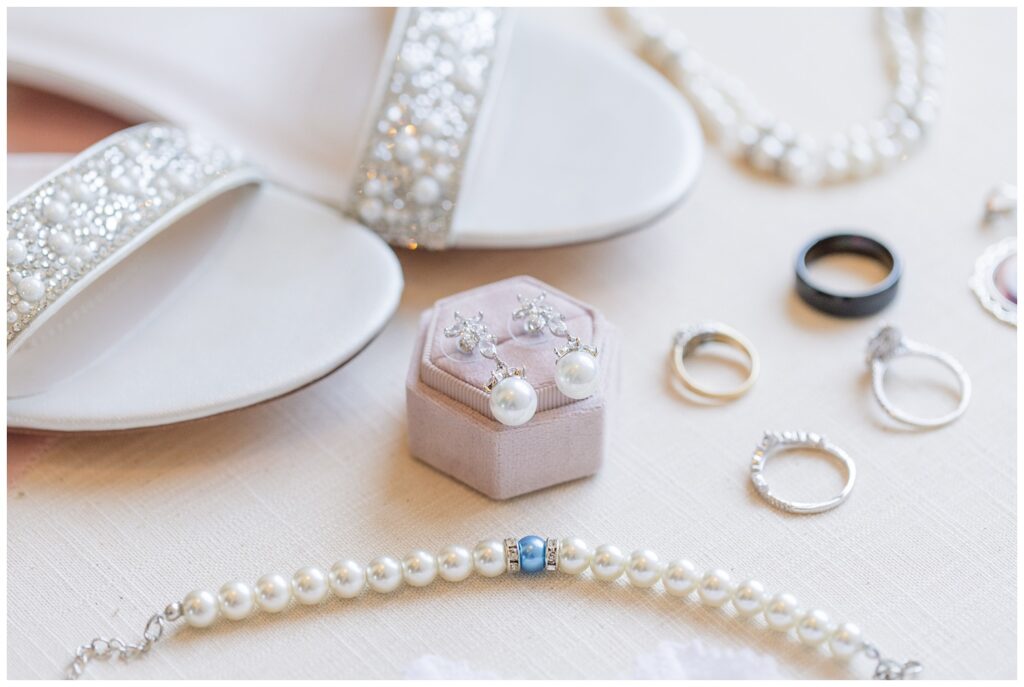 bridal details of earrings sitting on a pink ring box
