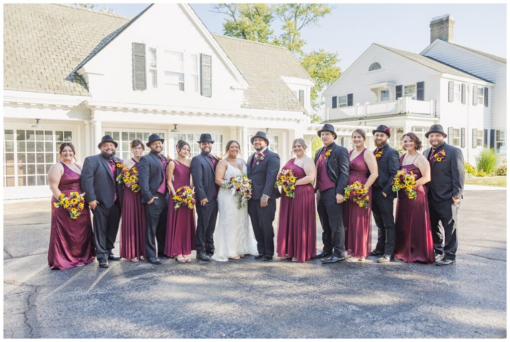 full wedding party posing outside in front of the Christy House venue