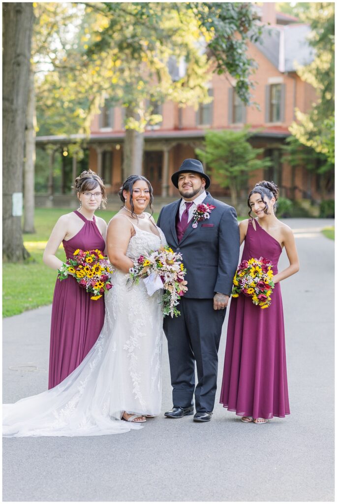 bride and groom posing with their sisters in front of the presidential house at the Hayes Center