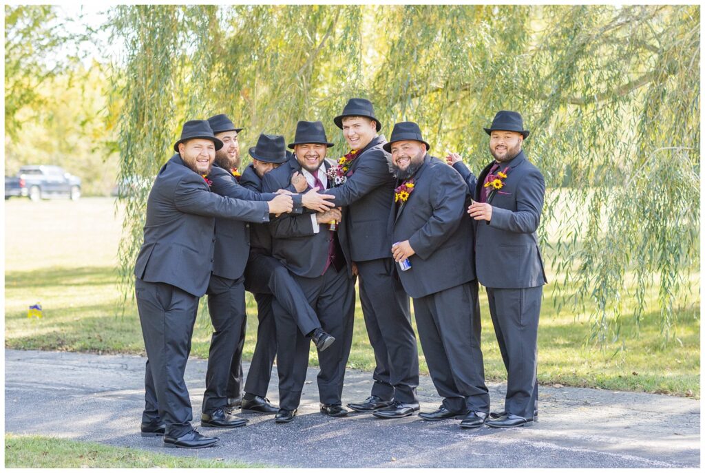 groomsmen posing together in front of willow trees at the Christy House