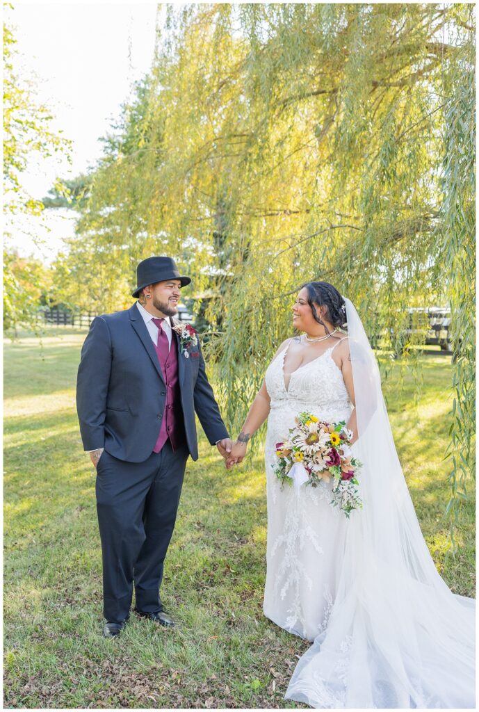 bride and groom holding hands under a willow tree in Fremont, Ohio