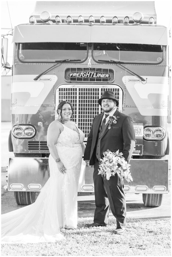 bride and groom holding hands in front of the groom's blue green tractor trailer truck