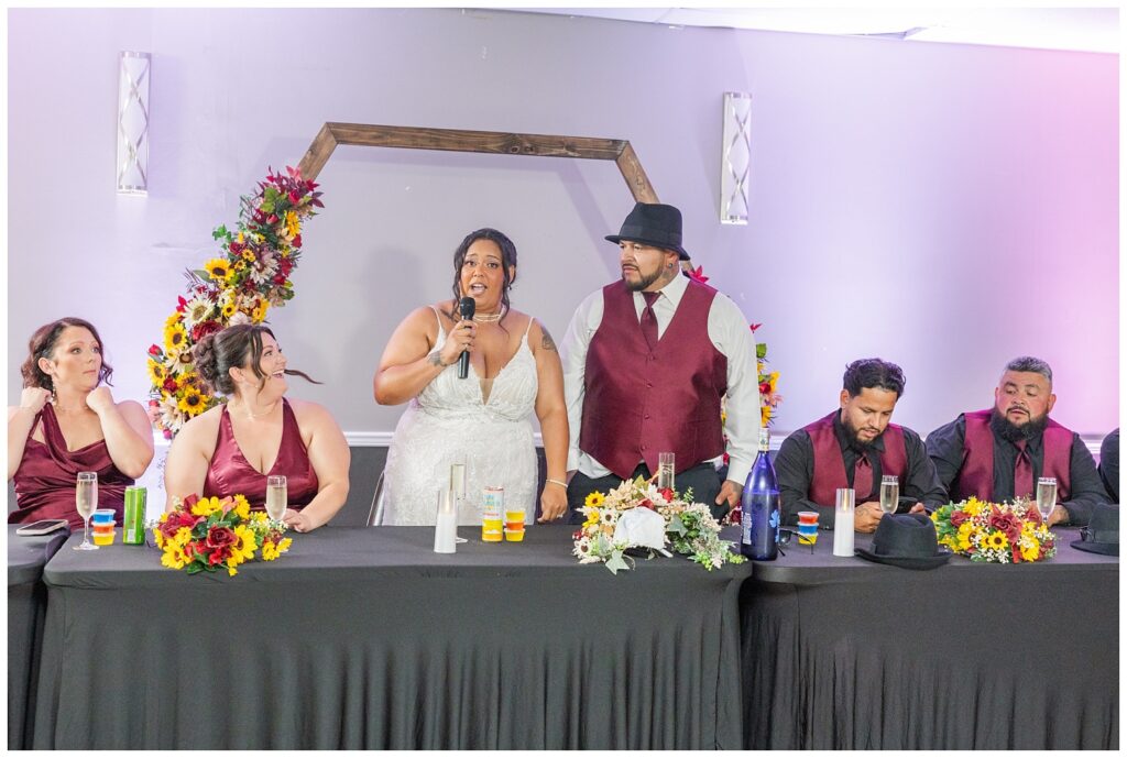 bride and groom saying a few words from their reception table at the Victor's Center