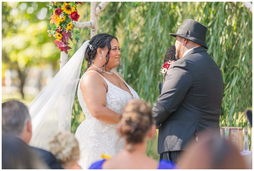 bride and groom exchanging vows outside in front of a willow tree