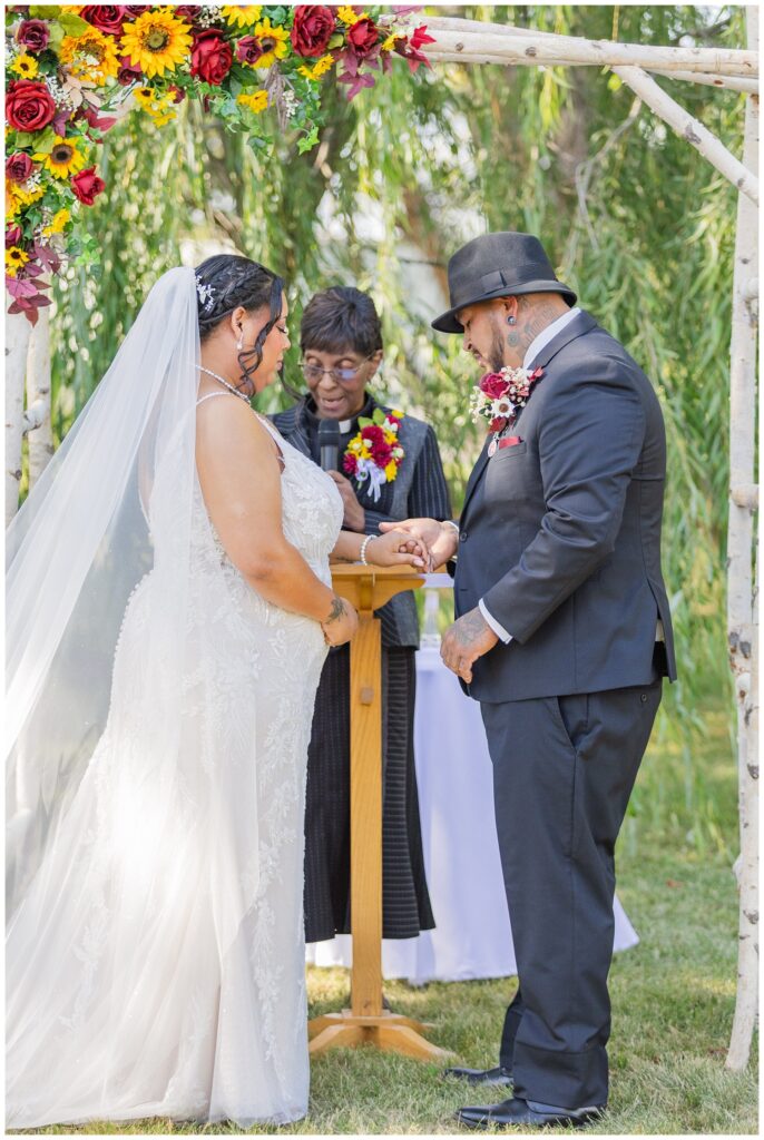 groom holding the bride's hands as they exchange rings outside at the Christy House venue