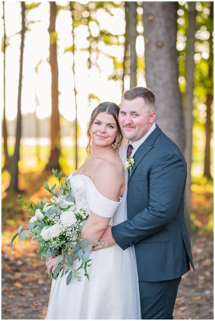 groom holding the bride from behind while the bride holds her bouquet