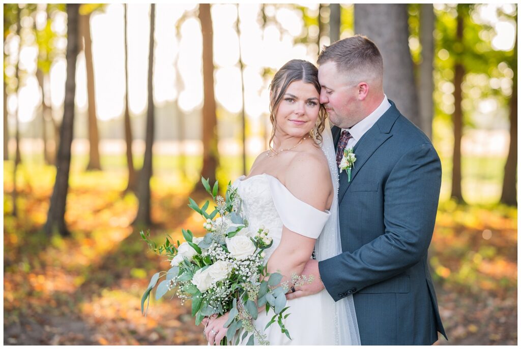 groom holding the bride from behind as he nuzzles and she smiles