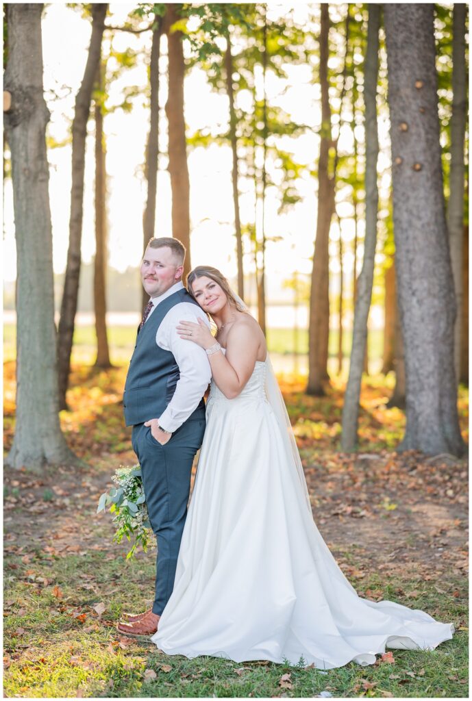 bride resting her head on the groom's back from behind as he holds her bouquet