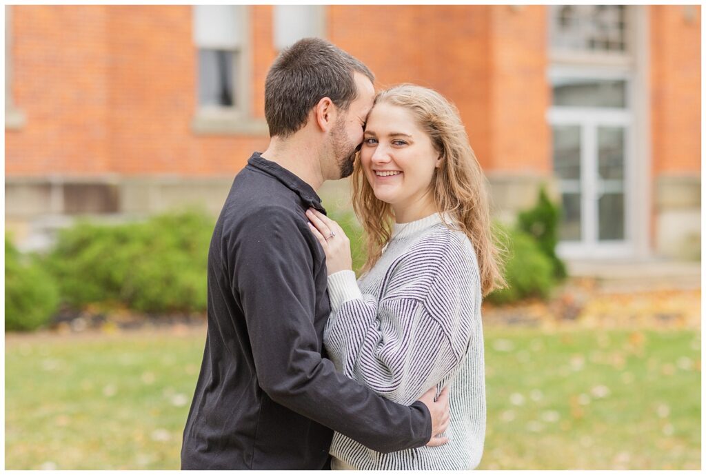 man giggling into his fiance's cheek while posing on Heidelberg University's campus