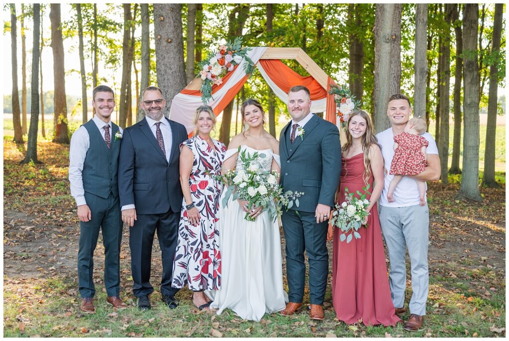 bride and groom with bride's family for outdoor portraits at Tiffin, Ohio wedding venue