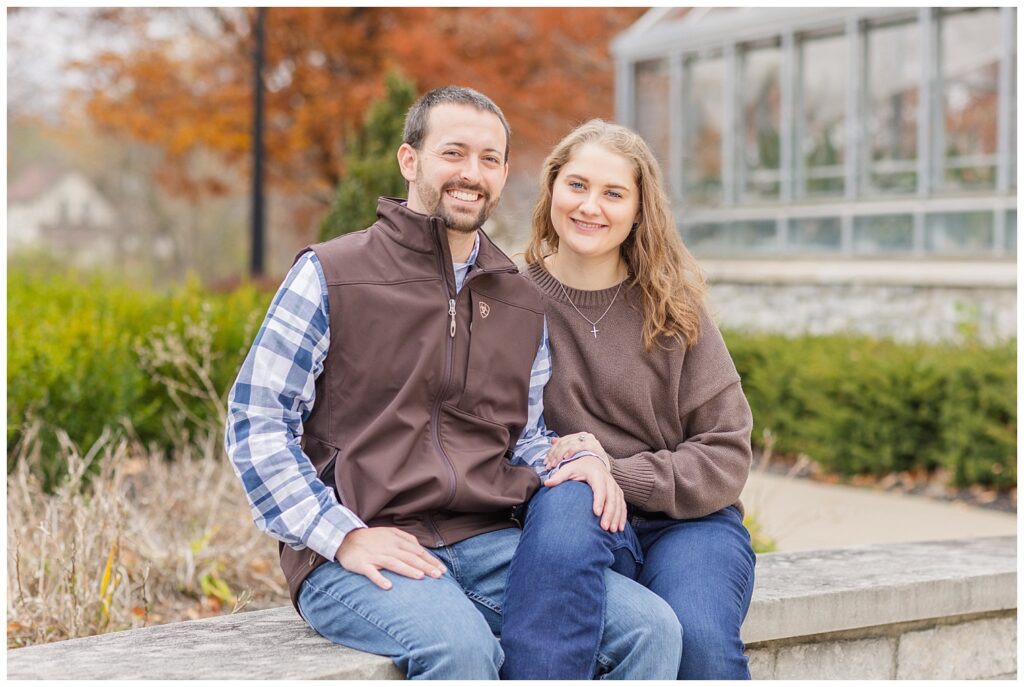 couple sitting on a stone wall outside at Heidelberg University at Tiffin, Ohio engagement session
