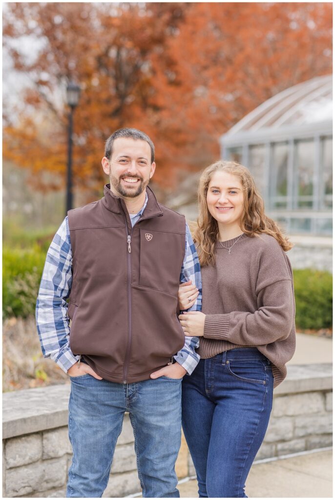 couple posing outside for engagement portraits next to a stone wall in Tiffin, Ohio