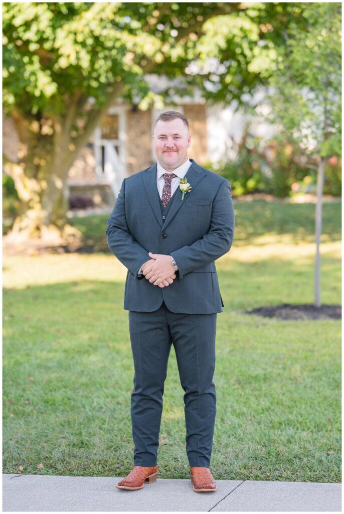 groom wearing a dark gray suit posing outside for portraits in Tiffin, Ohio