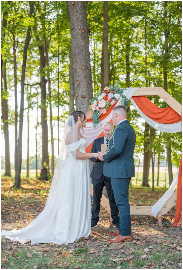 wedding couple holding hands at the altar in front of trees at Tiffin, Ohio venue