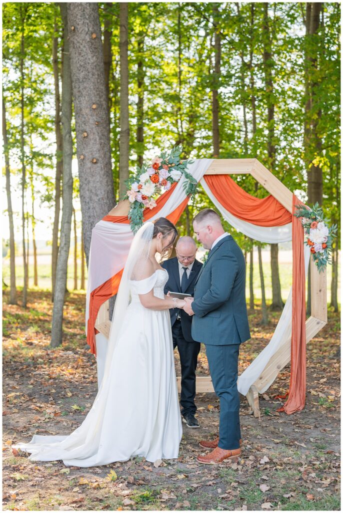 bride and groom exchanging rings during outdoor ceremony at Tiffin, Ohio venue