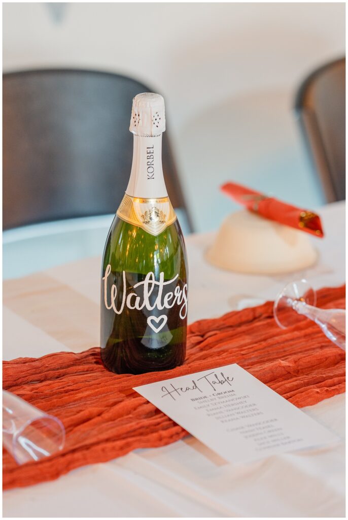 a specialty painted champagne bottle with the bride and groom's last name written 