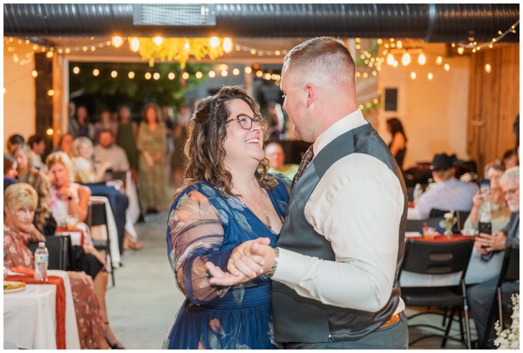 groom's mom smiling at the groom during their dance during a fall reception