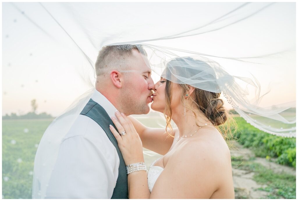 bride kissing the groom under her veil during sunset outside at Fremont, Ohio wedding venue