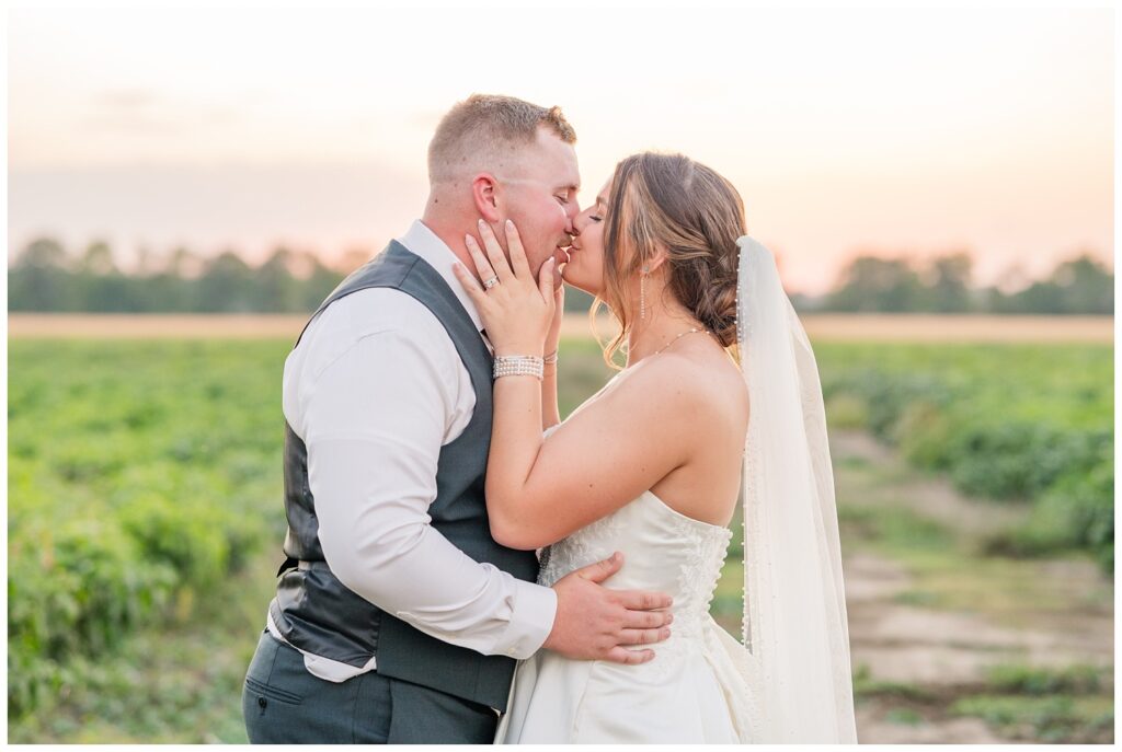 bride and groom share a kiss during sunset in the fields behind the Octagon House venue