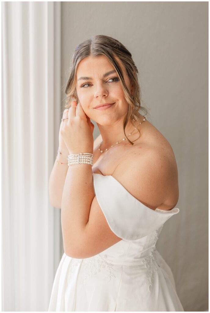 bride putting on her earrings next to the window at Fremont, Ohio wedding venue