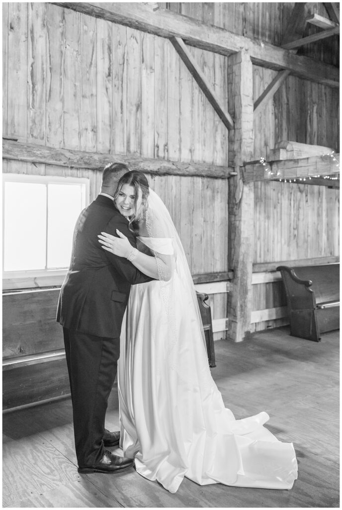 bride hugging her dad during their first look in the top of the barn