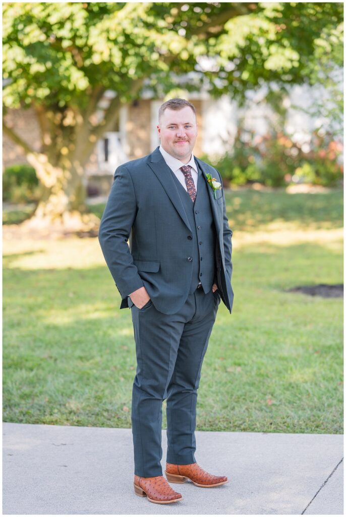 groom posing outside in front of a tree at the Octagon House wedding venue
