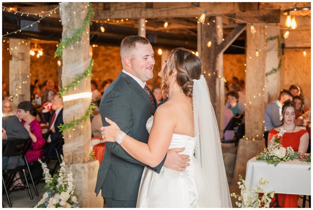 bride and groom dancing during the reception under the lights of the barn