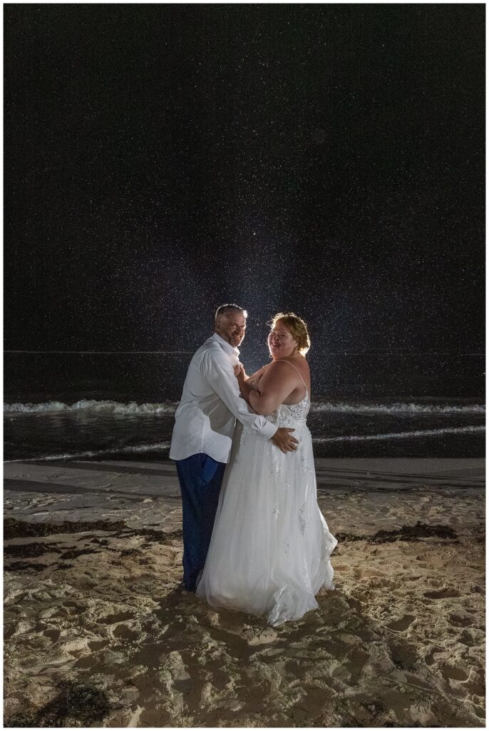 bride and groom posing at night on the beach after wedding reception in Punta Cana