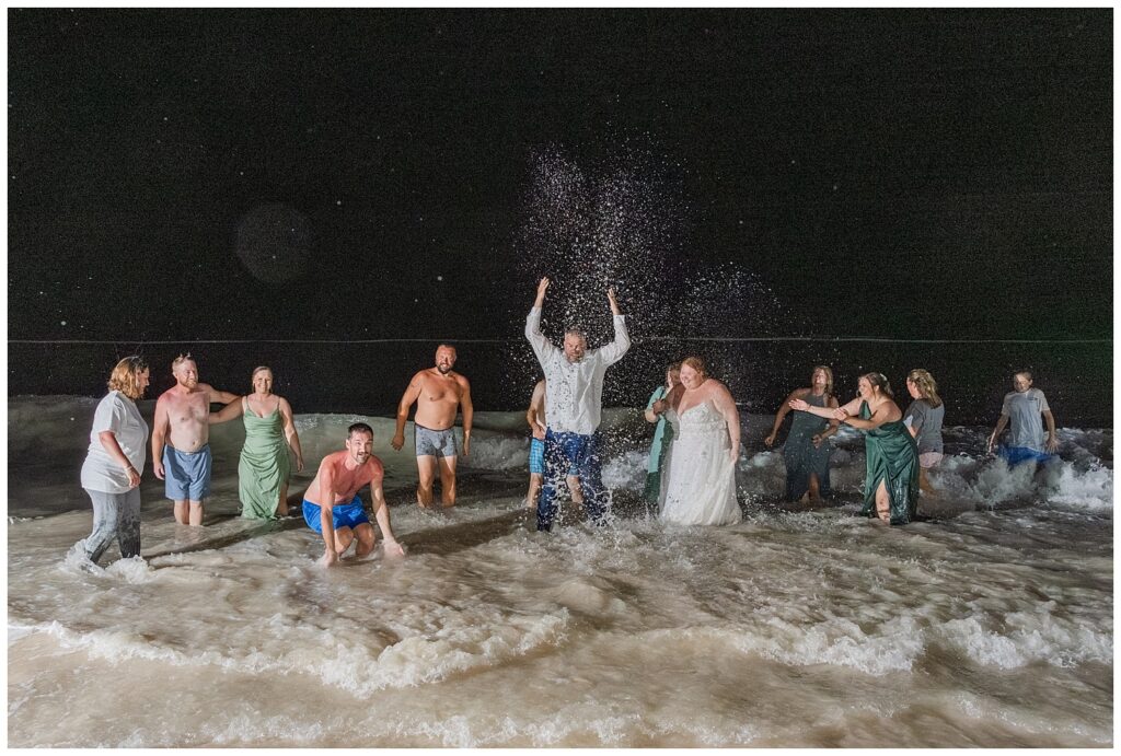 bride and groom along with friends splashing in the ocean at night after Punta Cana reception