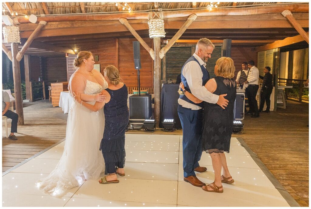 both the bride and groom's moms all dancing together while the guests look on 