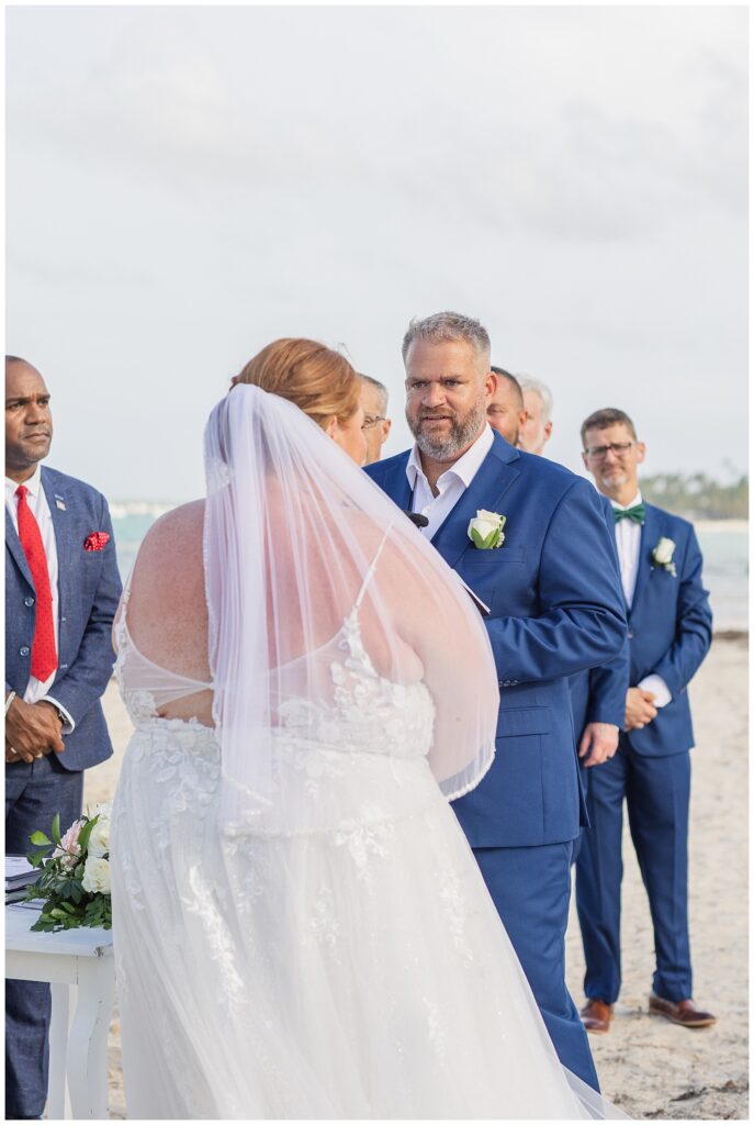 groom reciting his vows on the beach while the groomsmen look on during ceremony