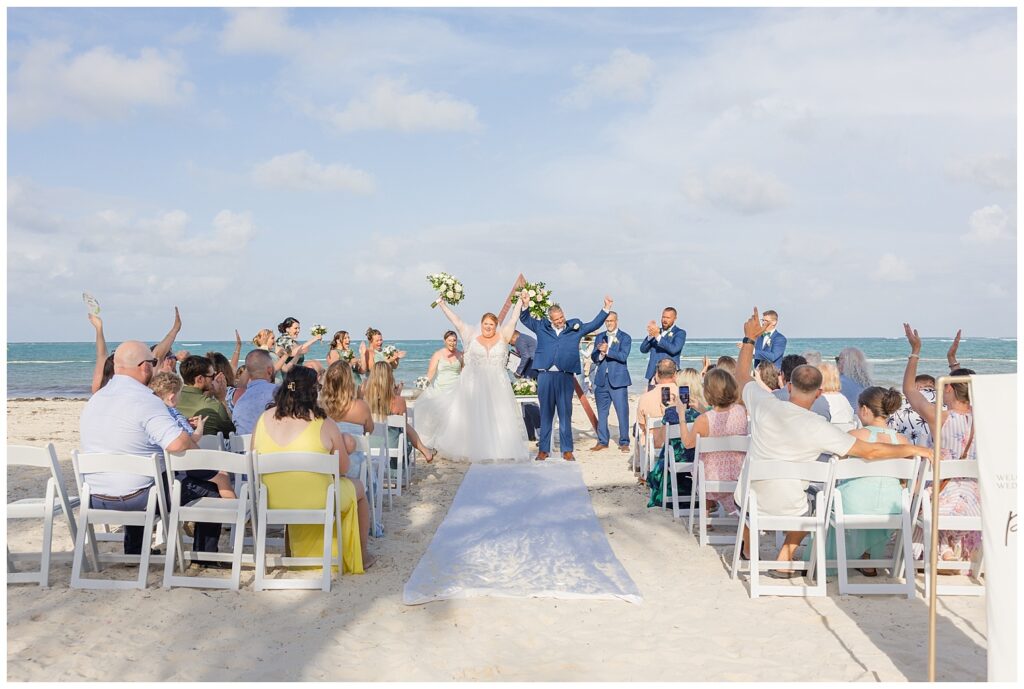 wedding couple cheering with arms up at the end of the ceremony on the beach at Punta Cana Dream Resort