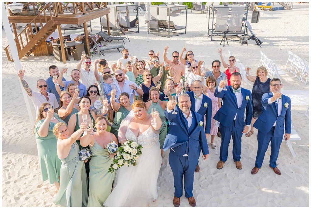 full group portrait of all wedding guests cheering with champagne on the beach in Punta Cana
