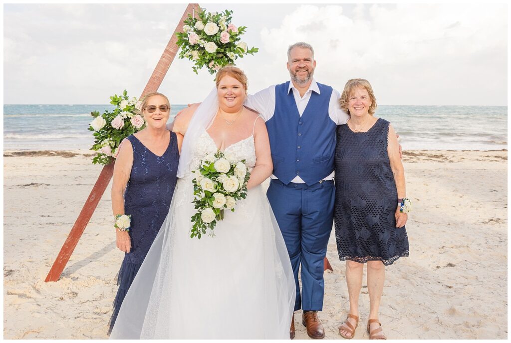 bride and groom posing with both their moms on the beach in Punta Cana for family portraits 