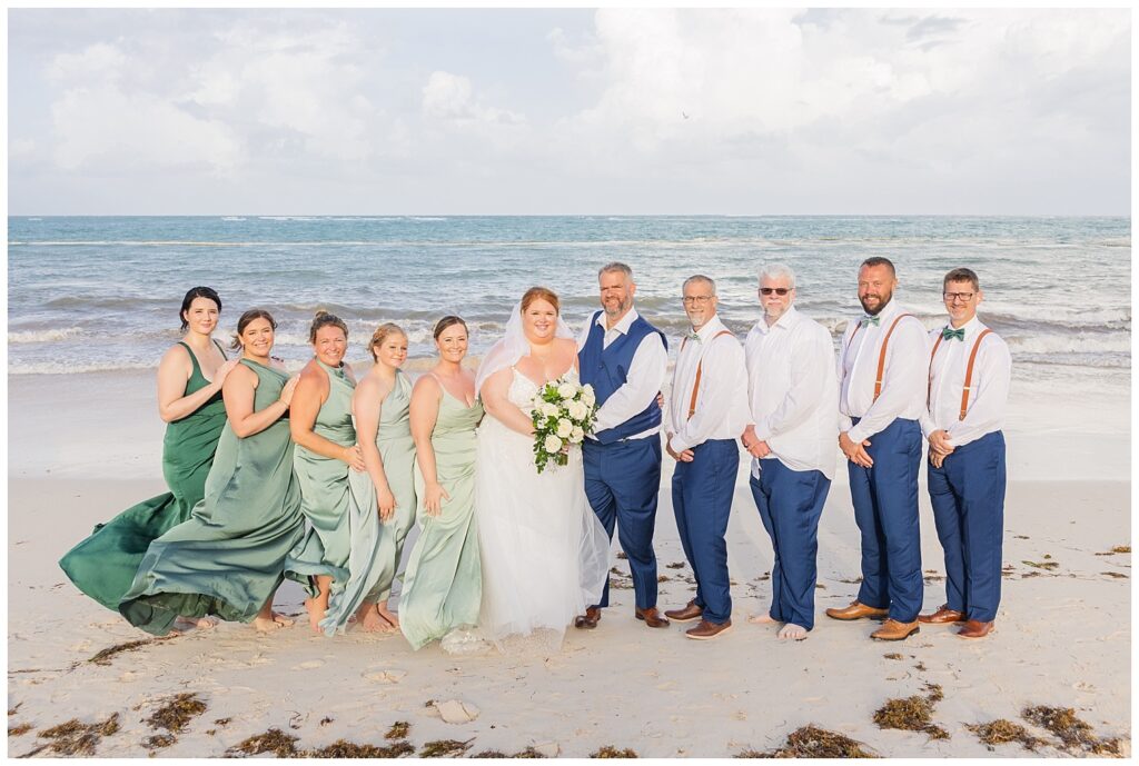 full wedding party posing together on the beach at the ocean at Punta Cana Dreams Resort